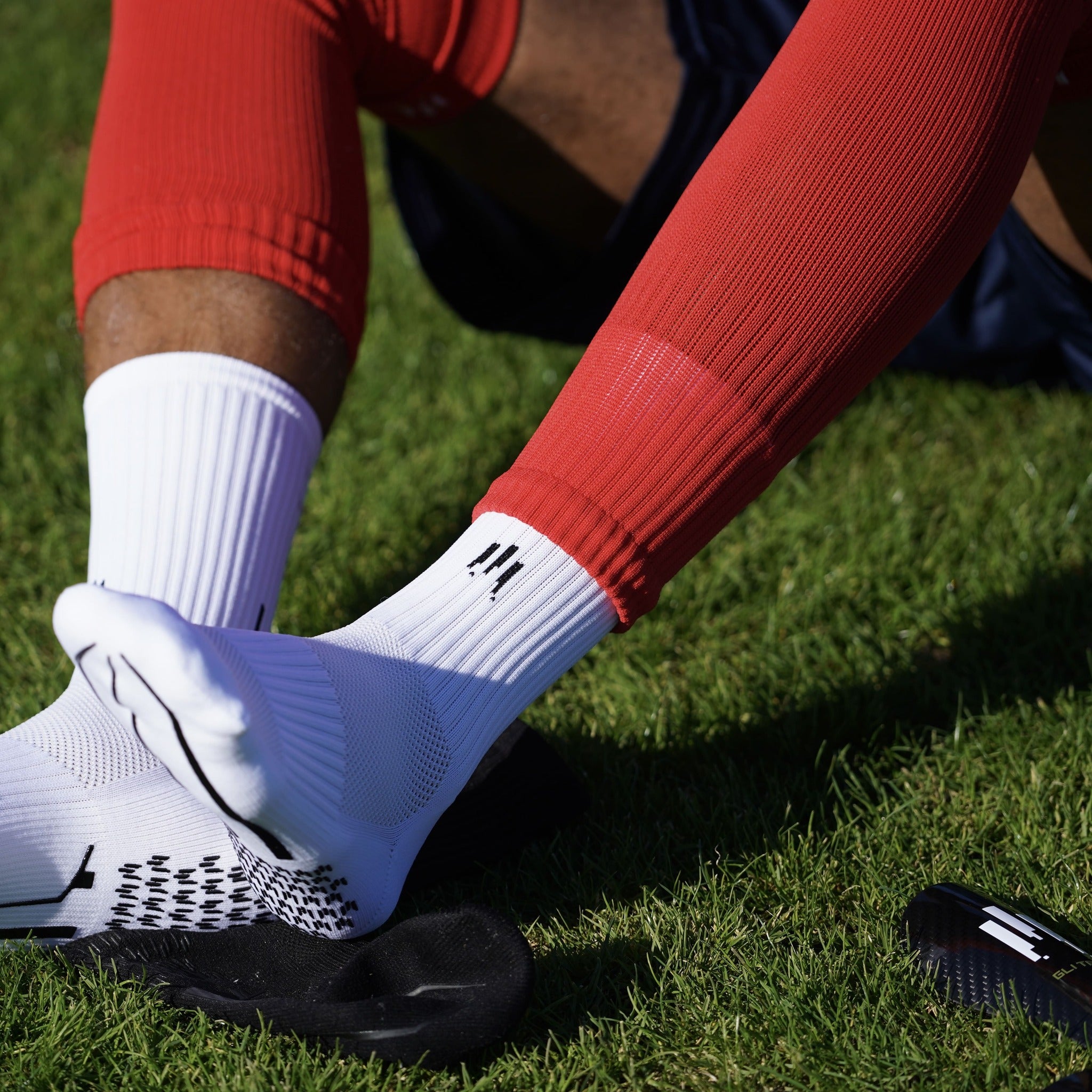 Joueur de foot avec des chaussettes antidérapantes blanches, chaussettes coupées et petits protèges tibias