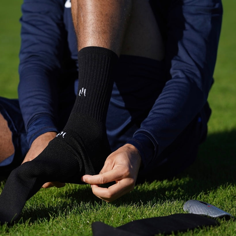 Joueur de foot avec des chaussettes coupées de football noires et chaussettes antidérapantes