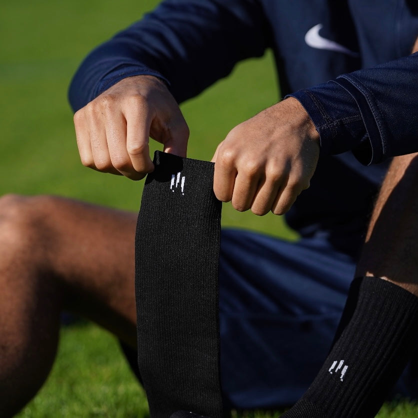 Joueur de foot mettant ses chaussettes coupées de noires
