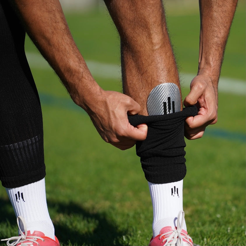 Combinaison des chaussettes de football antidérapantes blanches, petits protèges tibias en fibre de carbone blancs et chaussettes coupées noirs de la marque GLI TECH, vue rapprochée